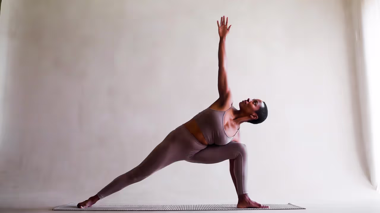 Person holding a strength-focused yoga pose like side plank in a quiet studio