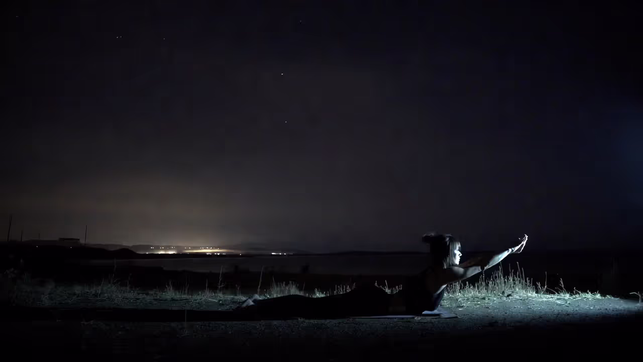 Person practicing yoga outdoors at night